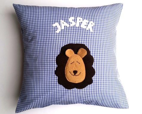 Kissen mit kariertem Design, auf dem ein Löwenkopf und der Name "JASPER" appliziert sind.
